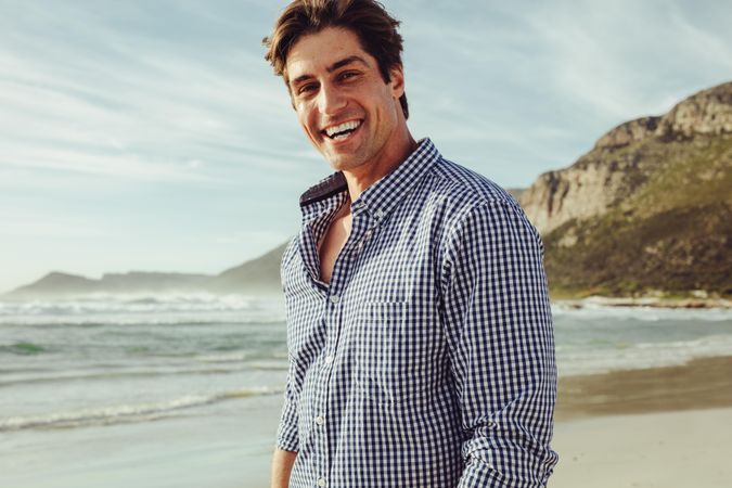 Handsome man smiling on the beach on a summer day