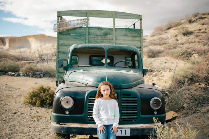 Concentrated girl leaning on abandoned car