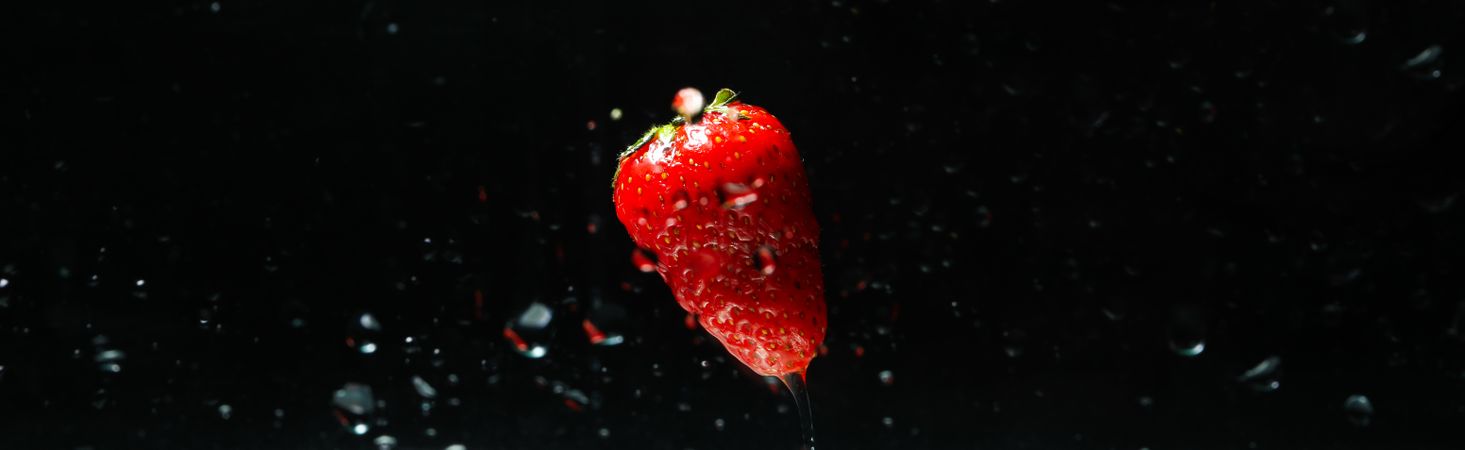 Side view banner of water on dark background with a floating strawberry