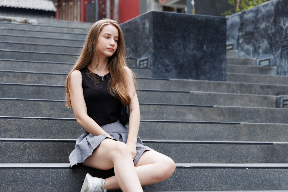 Portrait of unsmiling woman sitting on the stair looking in distance