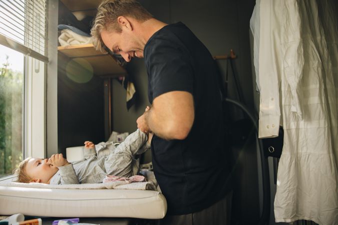 Caring father dressing his baby son in the morning