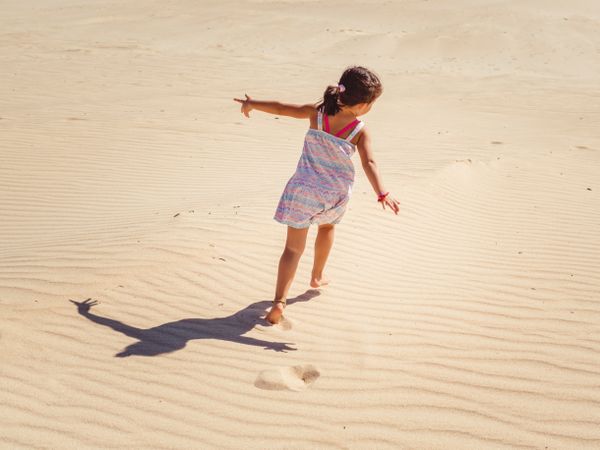Cute little girl playing with sand at beach