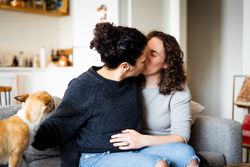 Wives tenderly kissing on sofa at home