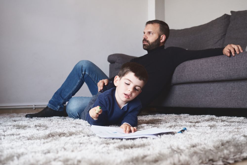 Son drawing on floor next to his father