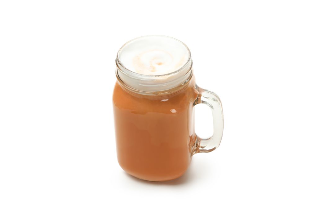 Glass cup of pumpkin latte isolated on neutral background