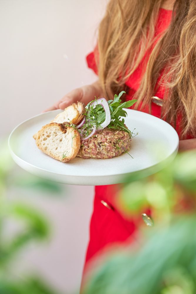 Unrecognizable woman holding plate with steak tartar