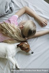 Top view of young girl lying on her stomach with her dog laying next to her 0V6QG0