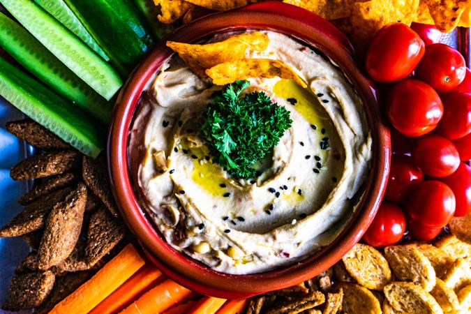 Top view of traditional hummus dish served with fresh veggies to dip