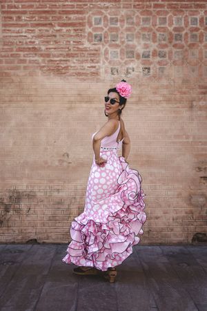 Passionate woman in flamenco dress dancing on street