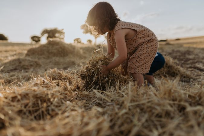 Cute girl lifting a hay from the ground