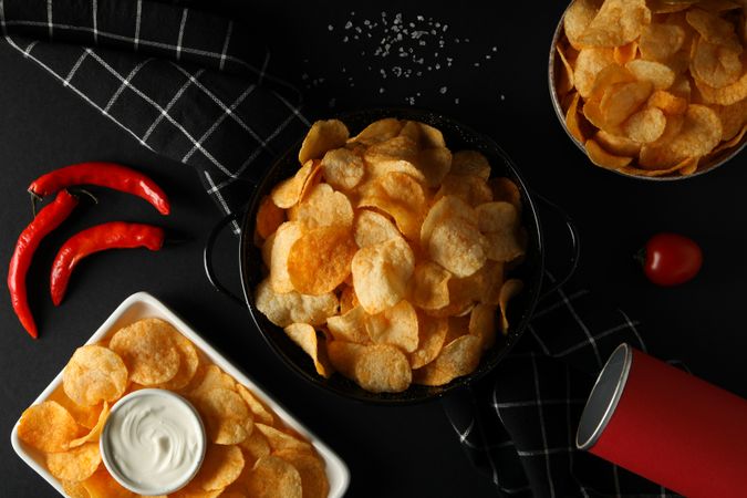 Potato chips in bowls with sauce on a dark background
