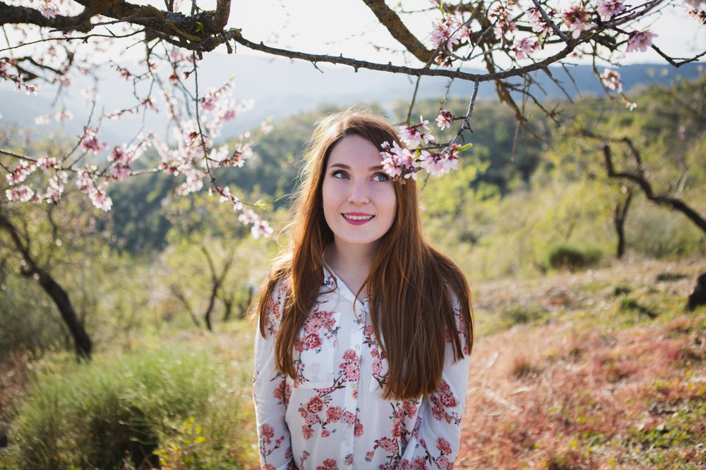 Young happy woman between trees in garden