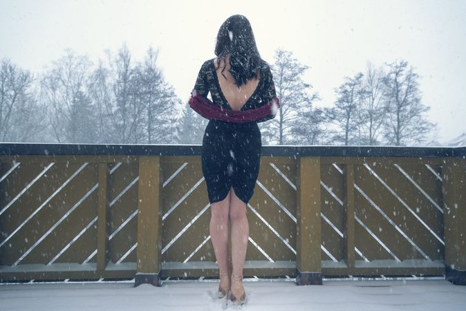 Woman in dark cocktail dress under snowfall