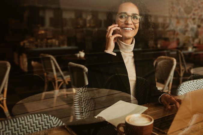 Woman sitting at cafe and talking on mobile phone