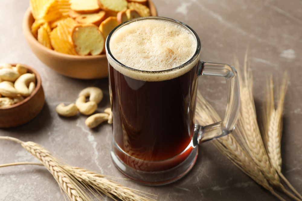 Beer, wheat and snacks on gray background, close up