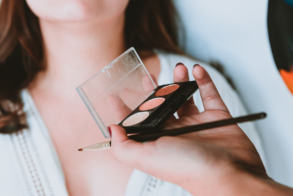 Woman hand with brush and powder for client