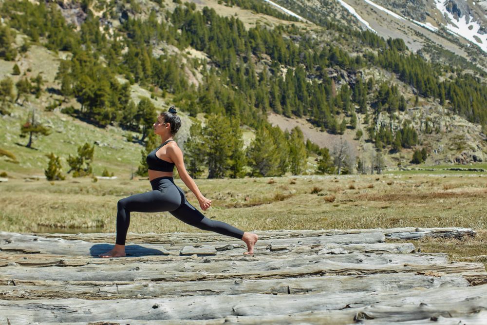 Side view of woman practicing yoga while balancing on a log