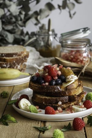 Honey pouring over fried toasts with fruit