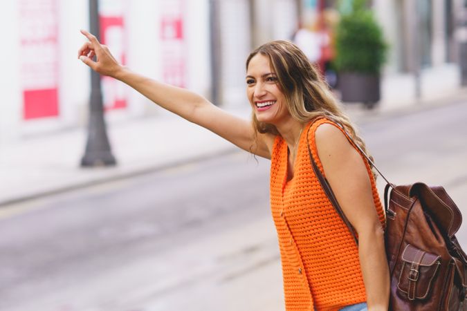 Woman in orange shirt hailing taxi
