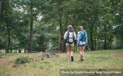 Two women friends with backpacks walking 4AzGNq
