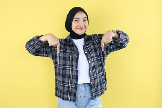 Excited Indonesian  Asian Hijab Young Woman with Casual Outfit Pointing at the Copy Space Below