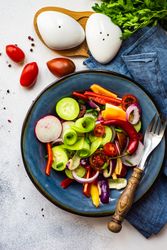 Top view of healthy raw vegetable salad served on blue plate