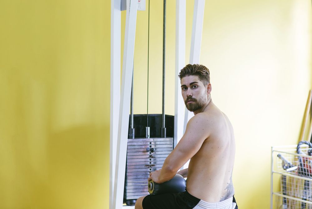 Man turning around while sitting on lat pull down machine, copy space