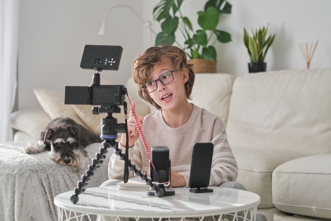 Boy pointing up and talking while shooting video at home