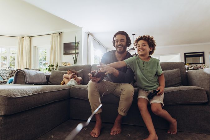Cheerful father and son enjoying video game at home