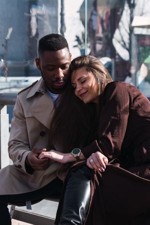 Romantic multiracial couple sitting on bus stop