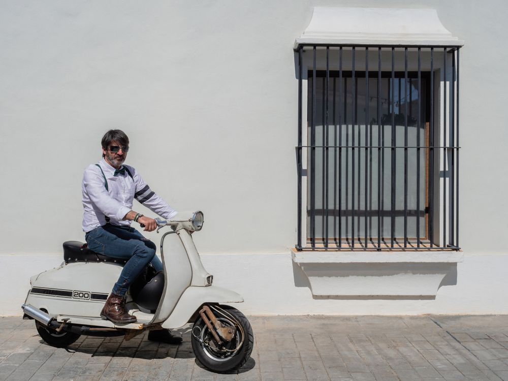 Trendy man sitting on vintage scooter