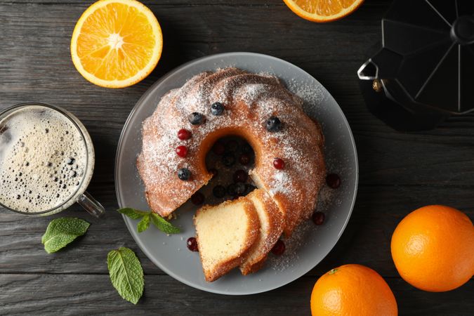 Cake with powdered sugar, berries and mint on wooden background, top view