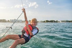 Content preteen child hanging on rope over sea during cruise