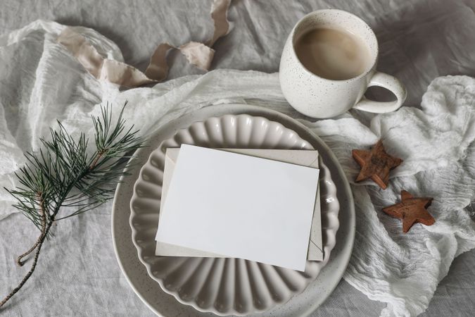 Blank card, invitation mockup on ceramic plate with pine branch and cookies on tablecloth