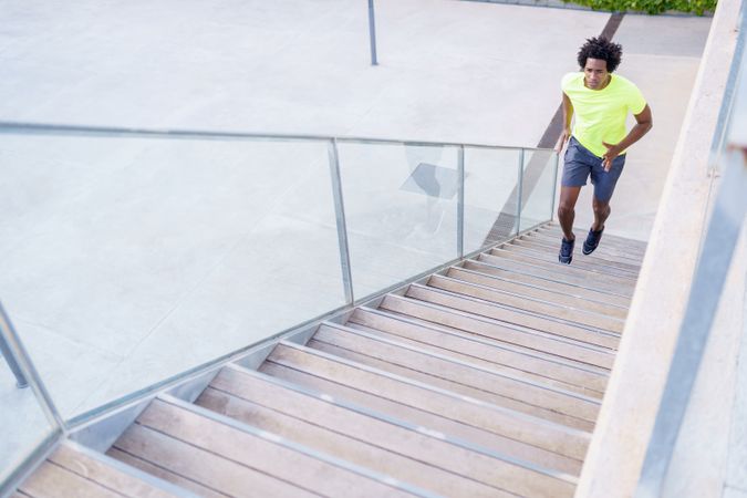 Fit man in neon T-shirt sprinting up outdoor staircase