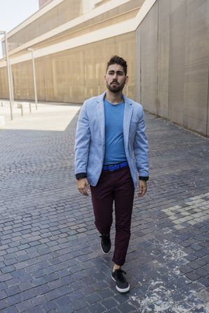 Young bearded man, model of fashion, in trendy clothes walking on street outside