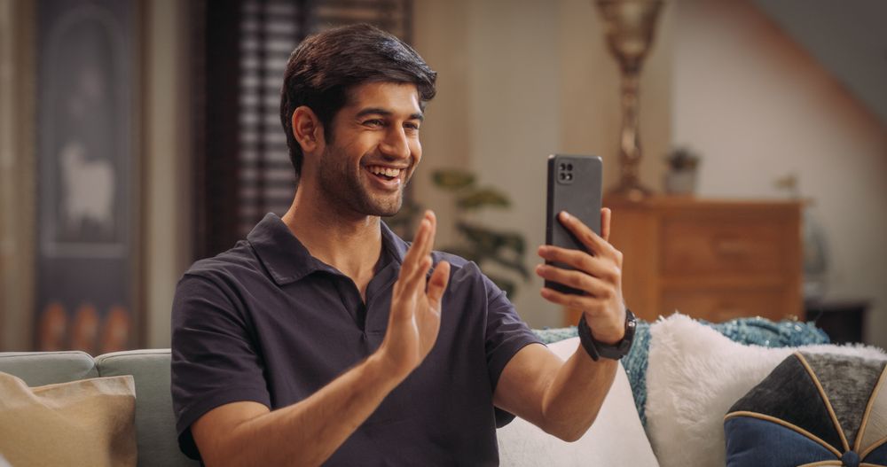 Indian Man Using Video Call On Smartphone At Home: Doing Remote Work, Conducting Video Meetings with Clients.