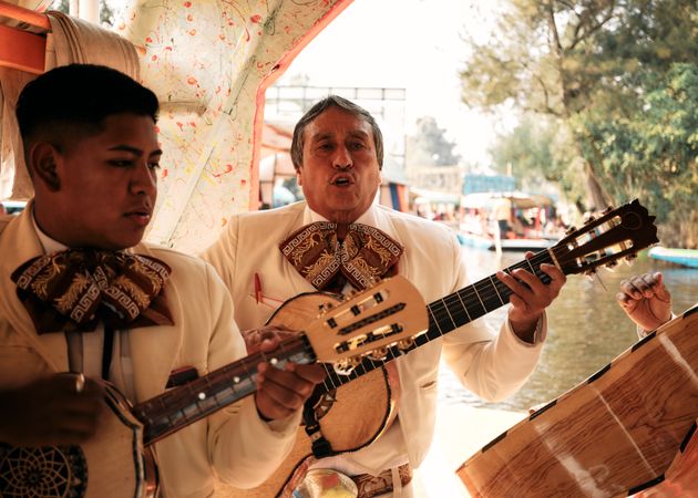 Two men in traditional Mariachi uniform with guitars