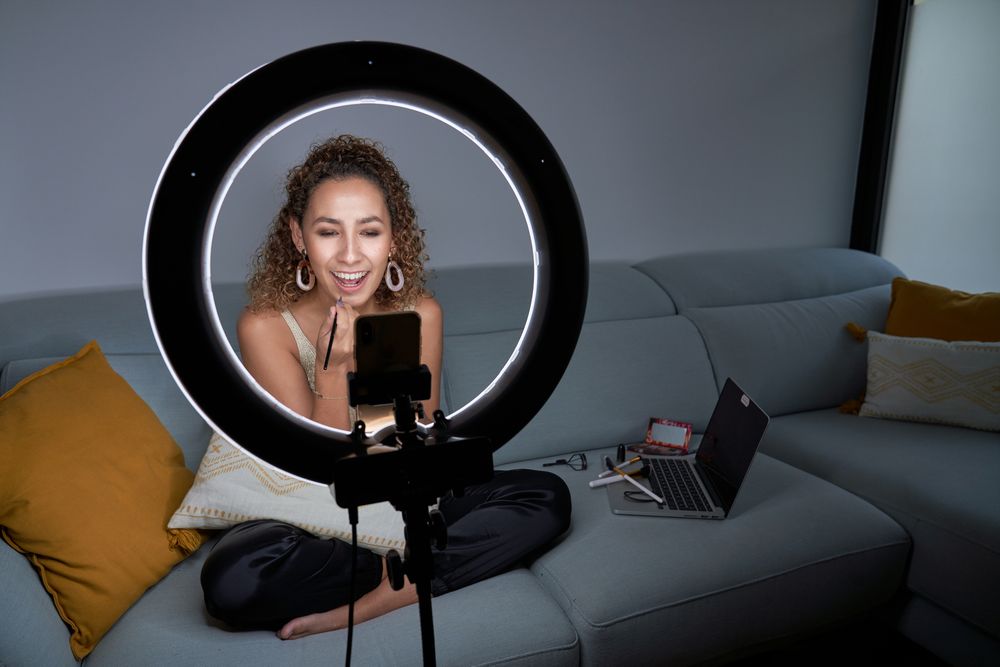Woman applying lipstick while streaming in social media on smart