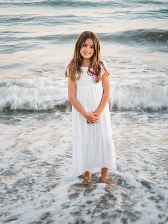 Smiling girl standing on seaside among waves