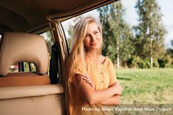 Blonde woman leaning on a van door in a field 56yQd0