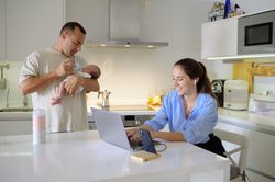 A man and woman holding a baby in front of a laptop