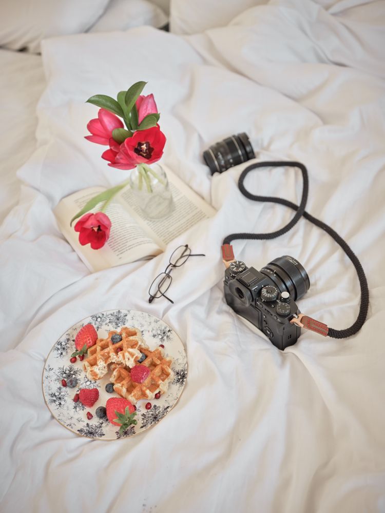 Waffles with photo camera and smartphone on bed