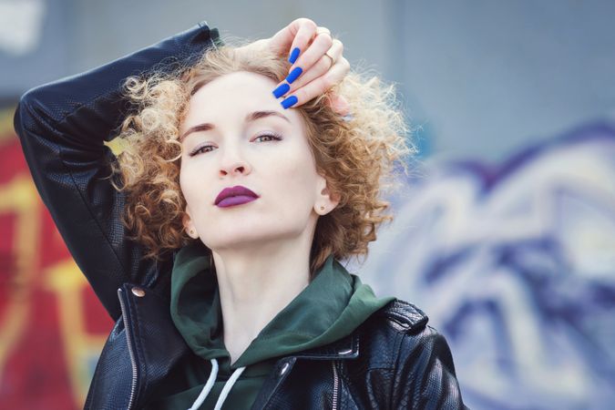 Cool curly haired female in leather jacket outdoors
