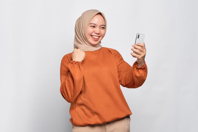 Muslim woman laughing at something on her smart phone