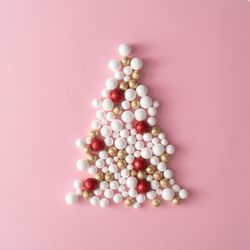 Christmas tree made of gold and red glitter ball decoration on pink