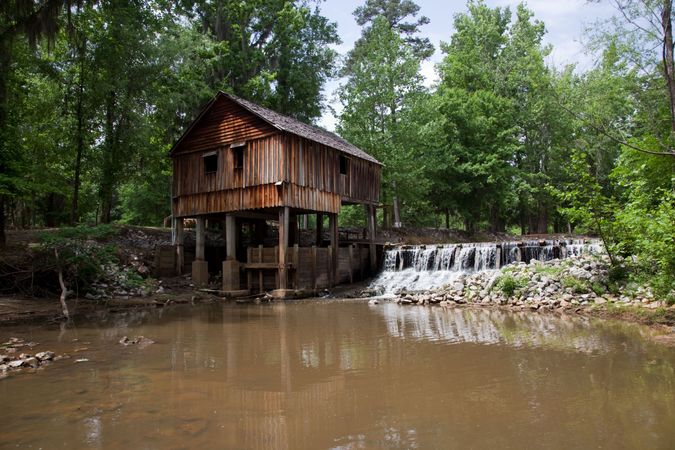 Rustic cabin mill on stilts over creek in forested Alabama countryside
