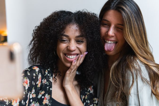 Crop smiling multiracial girlfriends taking selfie on smartphone
