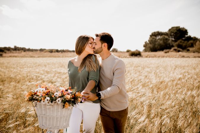 Sincere lovers posing by bicycle on rye field
