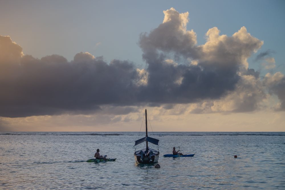 Two people kayaking near another boat at dusk